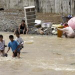 A river crossing as others clean belongings after floods receded on Saturday in suburban Montalban, east of Manila. (AP)