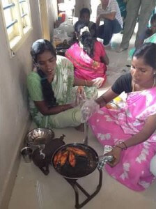 Women in the Trust Group fry seer fish with the travelers.