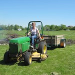 International Business Development’s Mary clears brush with the tractor.