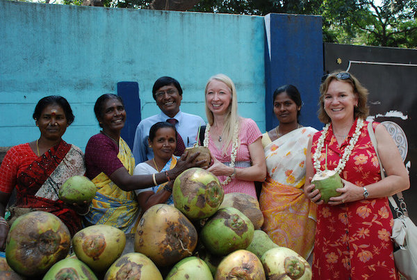 Travelers Wendy Cox (middle) and Jill Smith (far right) with clients, coconut milk vendors, in India