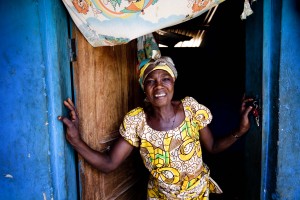 Adwoa in front of her new front door that help her family feel safer at night and protects her business inventory from burglaries.