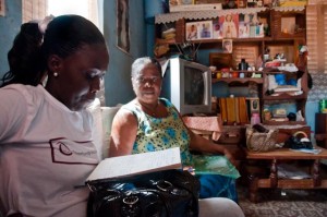 Loan officer Abena Sarpong (pictured left) and Beatrice Boaten look over the Trust Group's membership register in Beatrice's sitting room. (Photo: Sara Joe Wolansky)