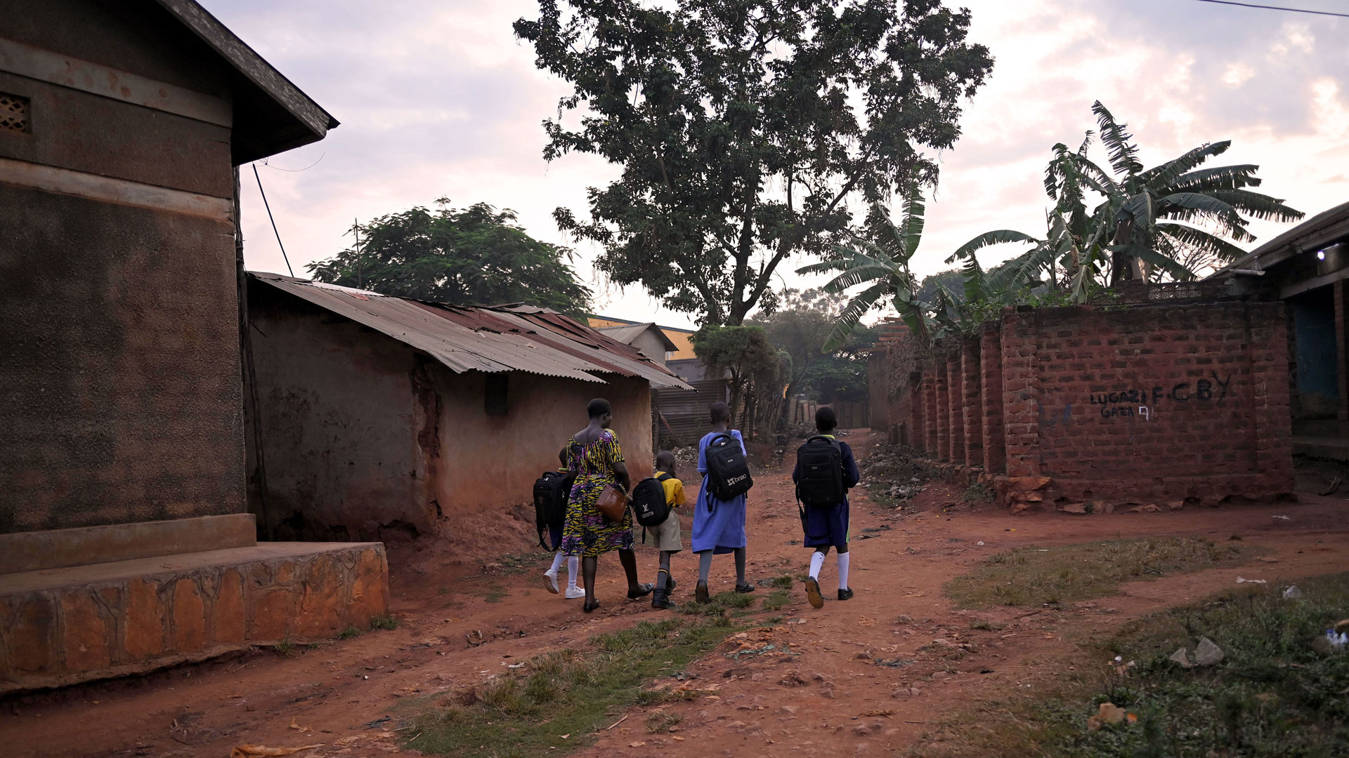 Annet, a teacher at an Opportunity-supported school in rural Uganda, walks home from school with her children