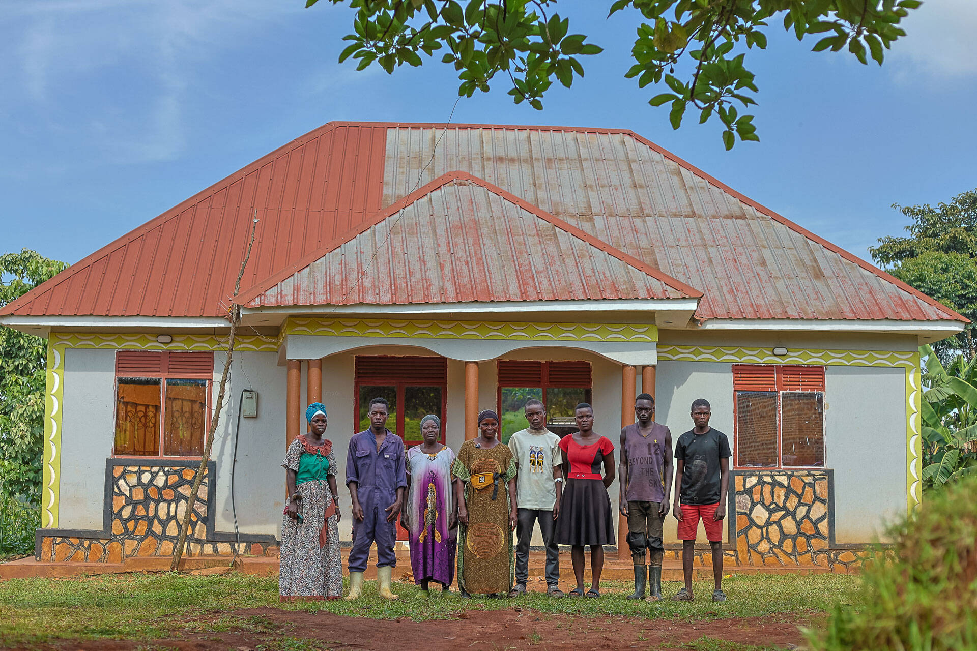 Namulondo’s family stands in front of their newly built home.
