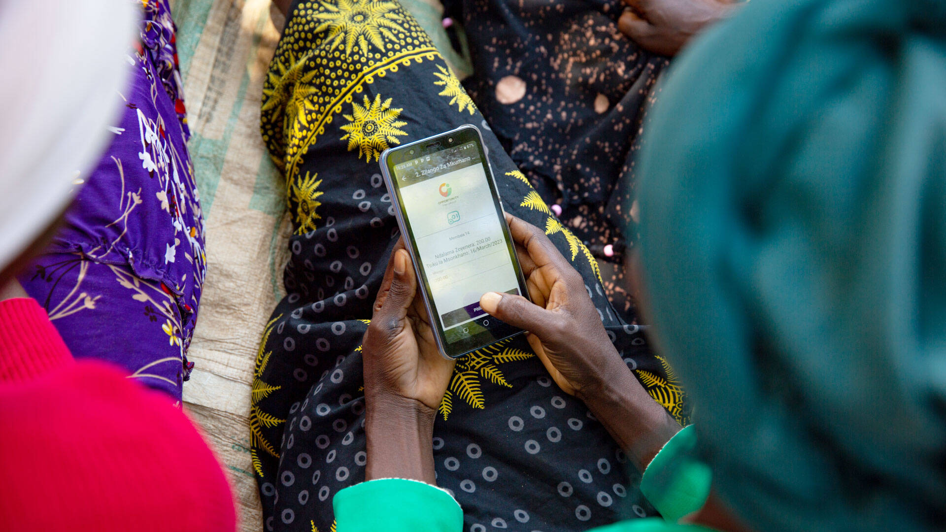 Twaina, secretary of her savings group, uses a digital app to take attendance and record payments in Malawi.